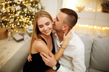 couple in love kisses and hugs on the sofa near the Christmas tree lights. New year's night. Christmas.