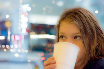 young girl drinking a soda in a fast food