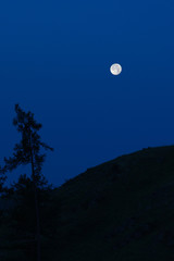 Naklejka na ściany i meble Bright full moon against blue night sky background