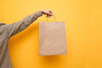 Background. A man in a shirt holds a paper shopping bag. Crafting a shopping bag in a man's hand....