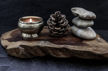 Pyramid of zen stones, Pine cones and Burning candle on old wooden background, Meditation concept,...