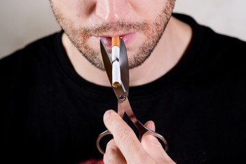 lower half of an unshaven man's face with a cigarette and scissors