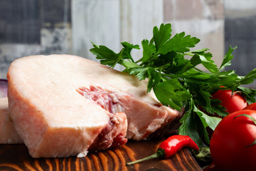 Lamb chunks on a wooden cutting board with spices and fresh vegetables
