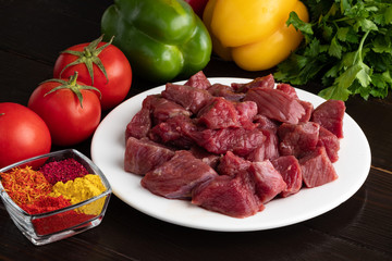 .Slices of raw meat on a white plate with spices and fresh vegetables. close-up