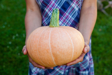 Woman holding a big pumpkin.