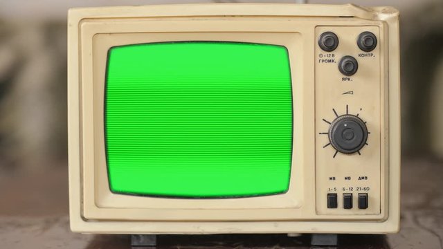 Old small vintage TV. 70s style television on vintage table. Gren screen with old TV screen effect.
