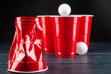 Wooden table with red cups and ball for beer pong