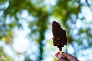 Chocolate ice cream with natural green bokeh as a background.
