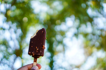 Chocolate ice cream with natural green bokeh as a background.