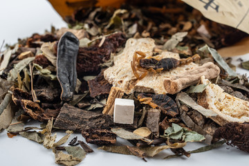 Chinese medicinal herbs pouring out of a paper bag on white background
