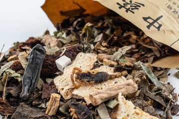 Chinese medicinal herbs pouring out of a paper bag on white background