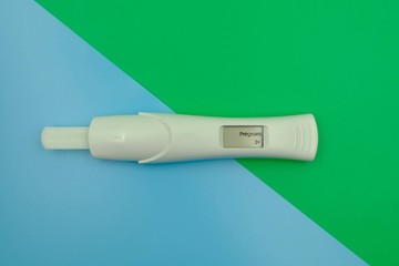 Digital pregnancy test with weeks estimator over blue green background