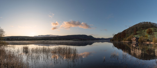 Epic vibrant sunrise Autumn Fall landscape image of Ullswater in Lake District with golden sunlight