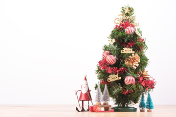 Decorated cute Christmas tree on a wooden floor with white background and toys, blank for festive design concept, close up.