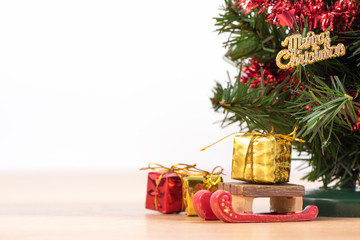 Decorated cute Christmas tree on a wooden floor with white background and toys, blank for festive design concept, close up.