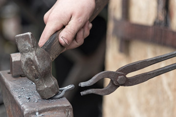 The blacksmith makes an iron loop with a hammer and tongs, forging on the anvil.