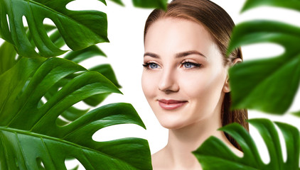 Young woman with smooth skin in tropical green leaves.