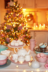 Fototapeta na wymiar Christmas decor in kitchen. Christmas dishes and sweets. Bright interior of New Year's kitchen. New year card template. The kitchen is white and pink colors. Christmas tree in the kitchen