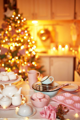Christmas decor in kitchen. Christmas dishes and sweets. Bright interior of New Year's kitchen. New year card template. The kitchen is white and pink colors. Christmas tree in the kitchen