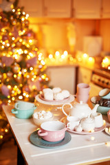Christmas decor in kitchen. Christmas dishes and sweets. Bright interior of New Year's kitchen. New year card template. The kitchen is white and pink colors. Christmas tree in the kitchen