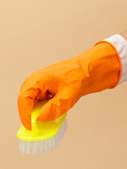 Woman's hand in protective glove with brush on beige background.