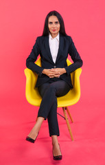 The boss. Full-length photo of a gorgeous CEO in a black suit, who is sitting in a yellow armchair...
