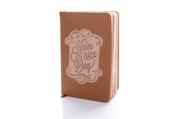 Brown notebook with text Have a nice day. Isolated