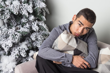Obraz premium Young happy man sitting on couch near christmas tree