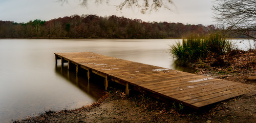Empty wooden dock leading into a smooth lake