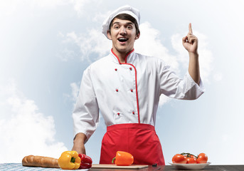 Young male chef standing near cooking table