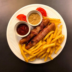 Berner Würstel ... Berner sausages wrapped in bacon with french fries and sauces. 