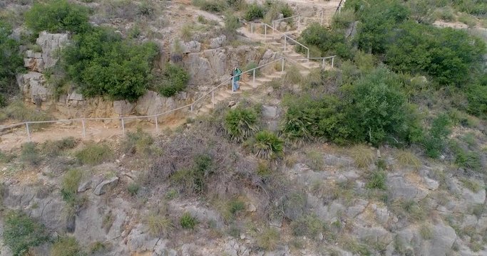 Abuelo de barba blanca canosa senderista baja escaleras de piedra en acantilado
