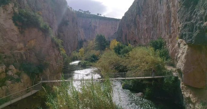 Senior excursionista cruza puente colgante en ca&ntilde;&oacute;n de r&iacute;a