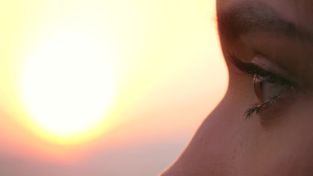 Pensive worried girl hoping - Close up side view portrait of young woman looking front on a background of sunset