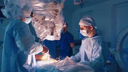 Operation in clinic. Specialists perform an operation through modern microscope. Surgeons working with medical instruments in operating room.