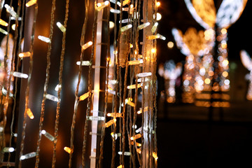 Part of Christmas decorative silver, white, yellow, golden flashing lights. Detail of New Year and Christmas decorations, string rice lights bulbs. Ornaments to christmas celebration, holiday scene.