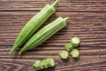 Farm fresh raw okra on wooden rustic table background.