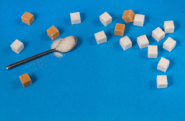 Cubes of white and brown sugar on a blue background.