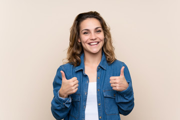 Young blonde woman over isolated background giving a thumbs up gesture