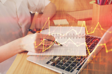 Financial charts displayed on woman's hand taking notes background. Concept of research. Double exposure