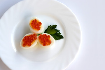 Red caviar. Sandwich with red caviar and quail egg. White background, white plate. Copy space