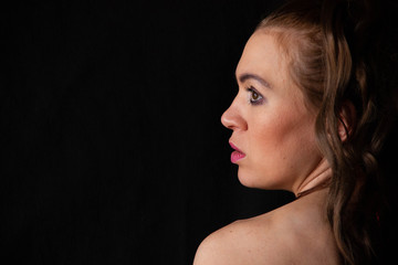 Fototapeta premium portrait of a sexy girl with long hair in a short dress with an open back on a black background