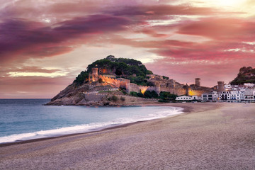 The Spanish city of Tossa de Mar located in Costa Brava is a coastal region of Catalonia. Beautiful sunset sky, an ancient cliff fort, sandy beach and the Mediterranean Sea. - 306535188