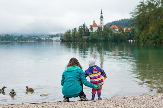 Mother and daughter playing on lake shore with romantic church in the bacground.