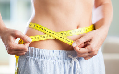 Young woman measuring her waistline