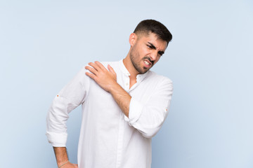 Handsome man with beard over isolated blue background suffering from pain in shoulder for having made an effort