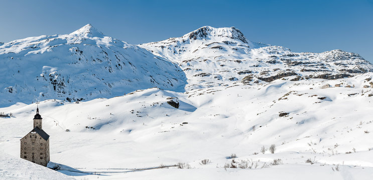 Winter panorama of snow covered Simplon Pass (Passo del Sempione) in Switzerland, close to the border with Italy in the Swiss Alps with Altes Spittel (old hospice) on the left