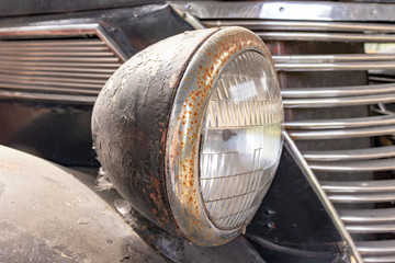 Fototapeta na wymiar A rusty old car front headlight close up