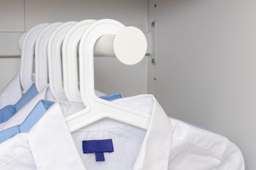 Fototapeta na wymiar Blue and white classic man's shirts on hangers in a wardrobe