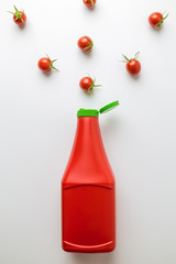 Obraz premium Flat lay of plastic bottle of ketchup with cherry tomatoes pattern on white background minimal food creative concept. Space for copy.